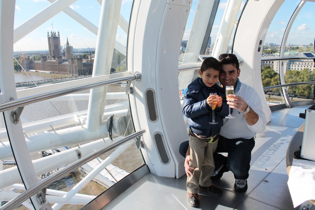 little boy and his dad holding glasses inside London Eye capsule posing for mums magazine