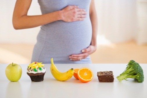 pregnant woman caressing her tummy while watching nutrients on the kitchen table 