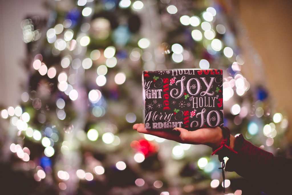 Christmas Gift handed over with christmas lights in the background