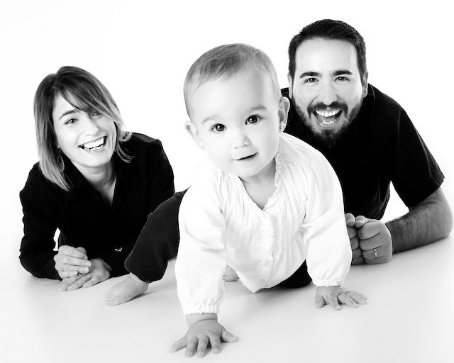 parents smiling at baby crawling 