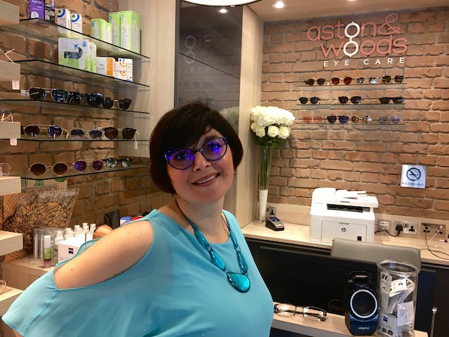 London Mums magazine editor Monica Costa wearing turquoise top posing with blue prescription glasses 
