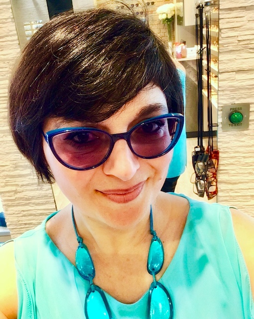 woman wearing turquoise top and necklace with blue spectacles posing for mums magazine