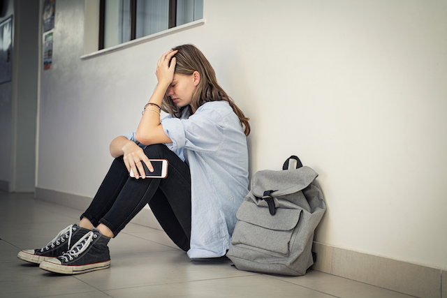 teenager girl sitting down desperate and worried