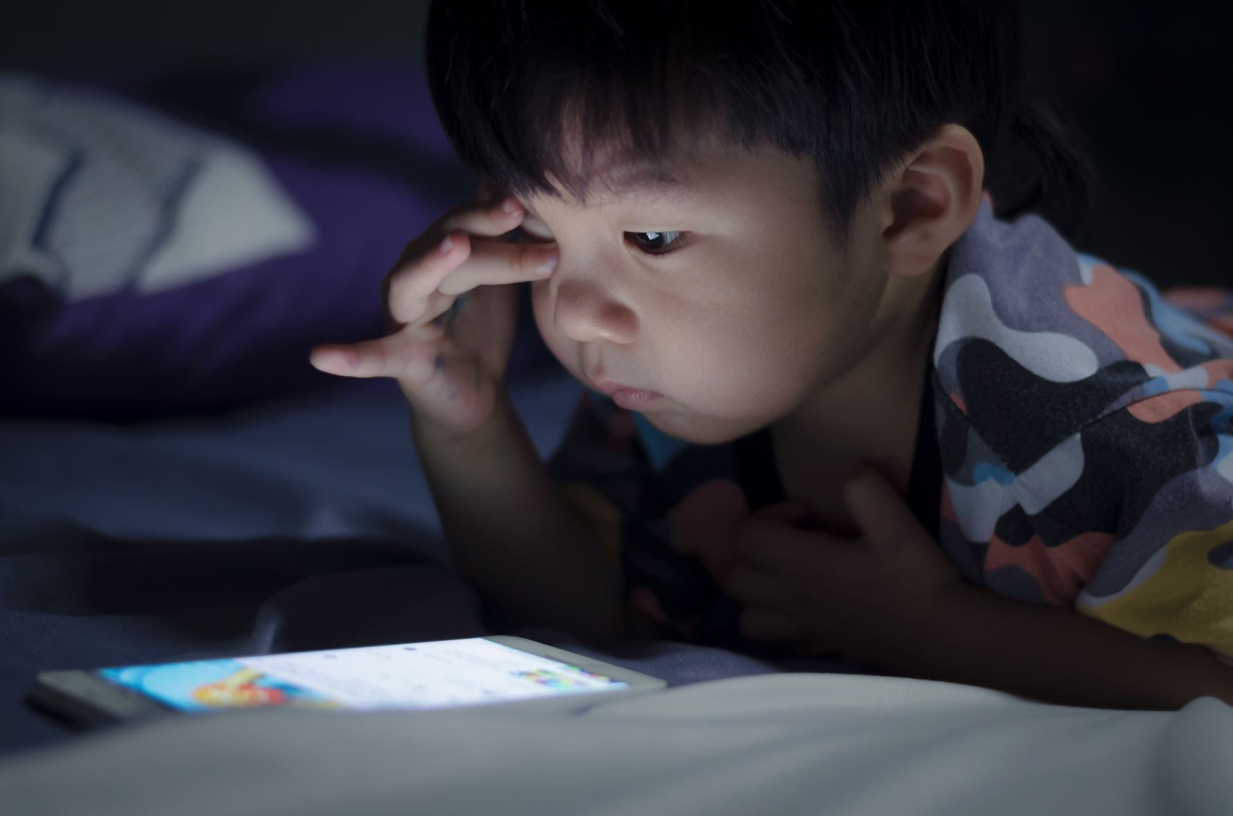 child playing on tablet under the duvet New research on children’s sleep habits and top 10 biggest bedtime battles