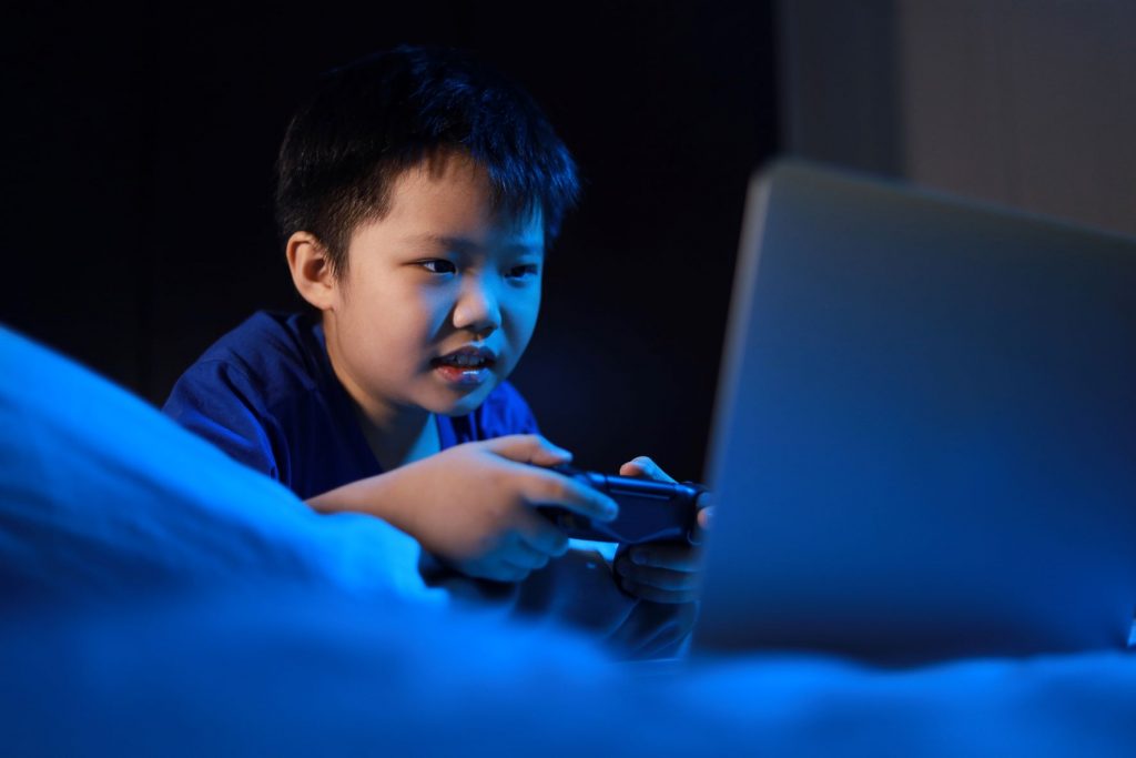 child playing on tablet under the duvet New research on children’s sleep habits