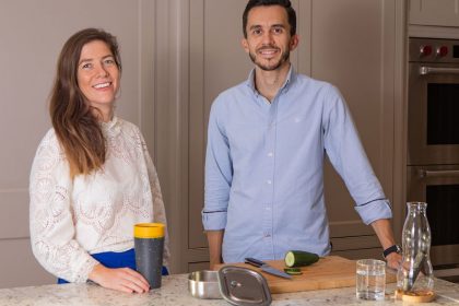 Couple husband and wife founders of the eco swap club posing in their kitchen for mums magazine