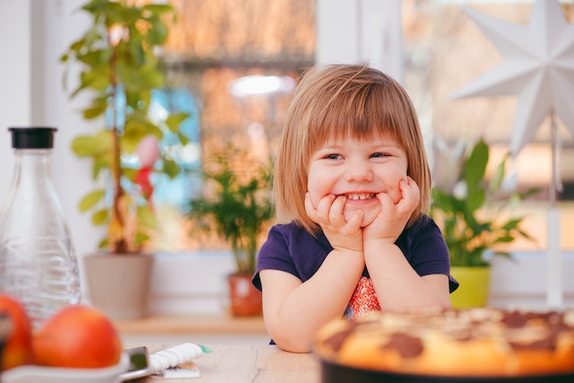 child with arms on kitchen table posing for mums magazine 