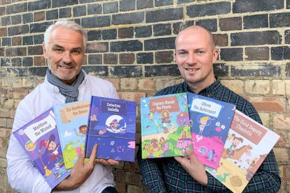 two dads hold customised books posing for mums magazine