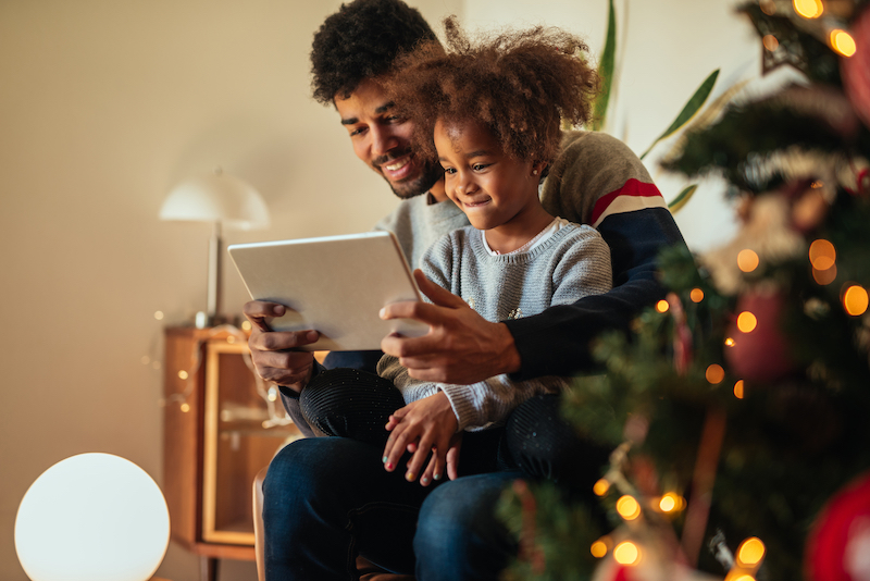 Cute african american girl using tablet with dad at home.