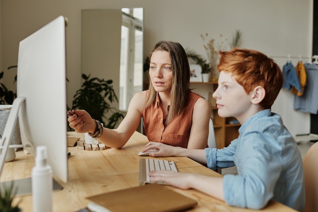 mum and son in front of the computer doing home schooling posing for mums magazine 