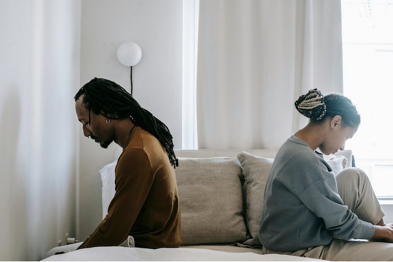 unhappy couple sitting on a bed looking away 